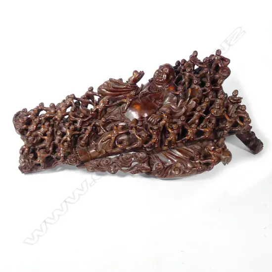 A vintage wood carving of a reclining laughing Buddha