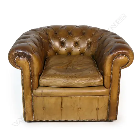 A vintage tan leather button back armchair,