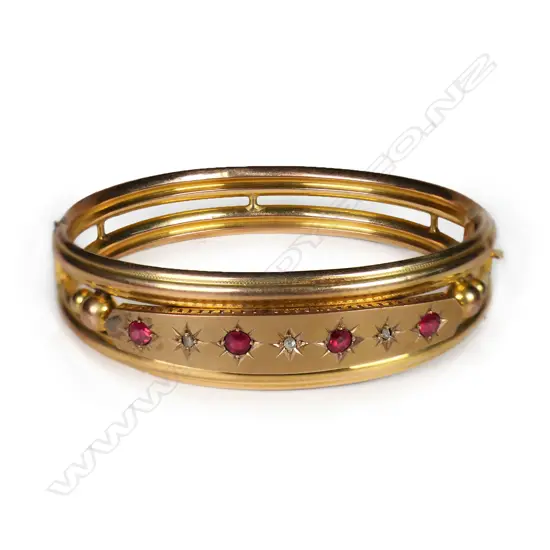 An Edwardian 9ct rose gold ruby and diamond hinged bangle,