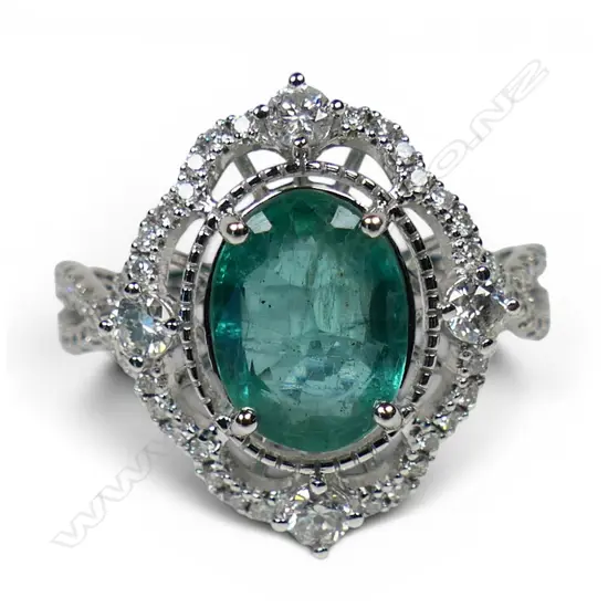A 14ct white gold emerald and diamond halo ring,