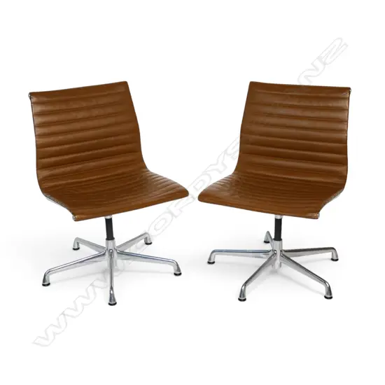 A pair of tan leather Eames conference swivel chairs,
