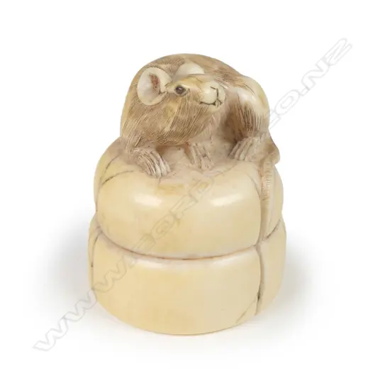 An antique Japanese carved ivory netsuke of a rat seated on two rice cakes