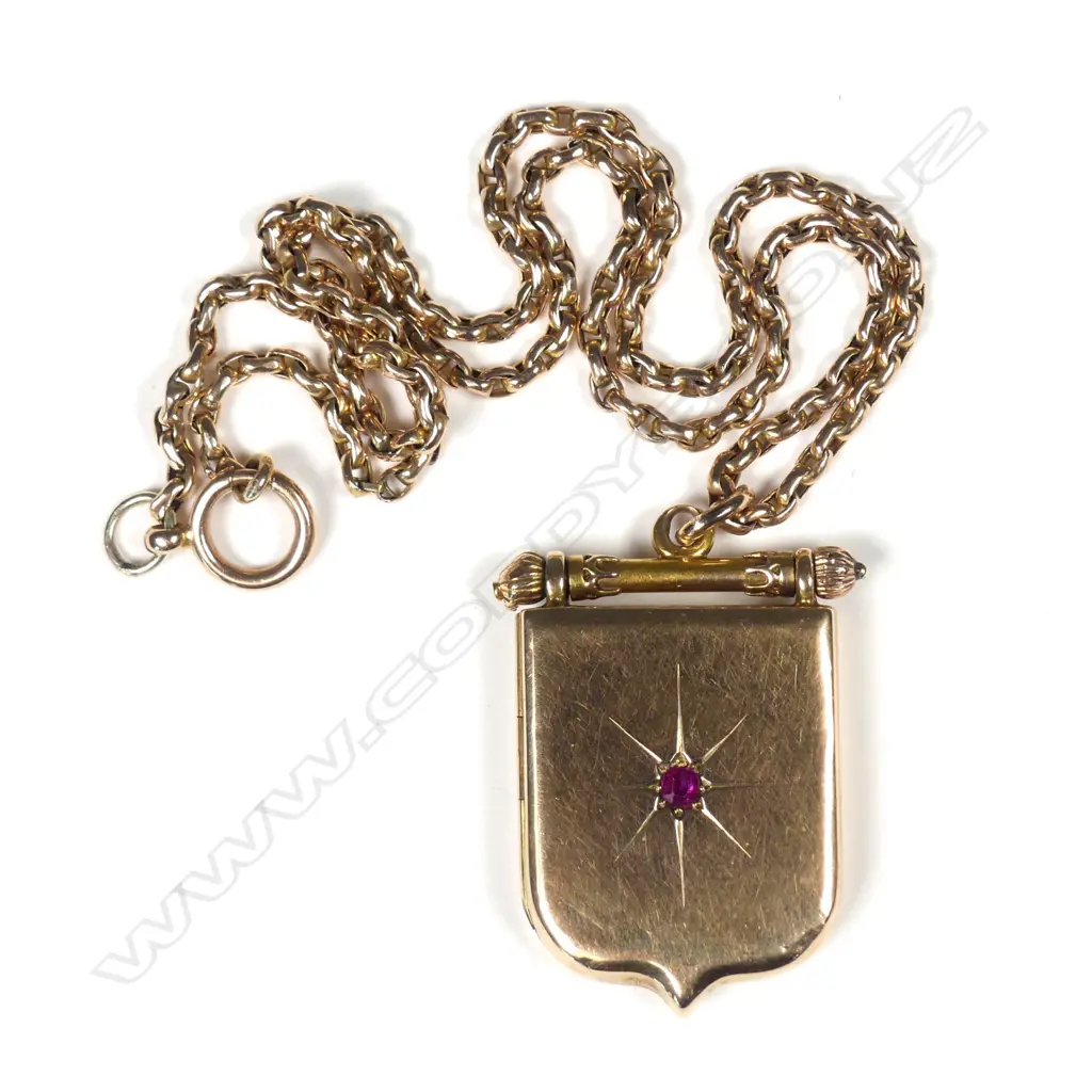 An Edwardian 15ct gold locket, shield form with small ruby star set to the front, (slight dent to bead top), the interior with glass for photos, together with a 9ct rose gold chain, 19.58gm. Valuation available. Image 1++