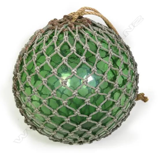 A large old glass fishing float with netting