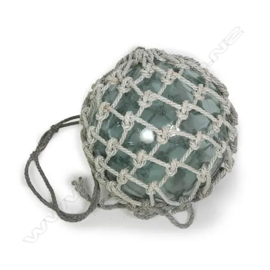A large old glass fishing float with netting