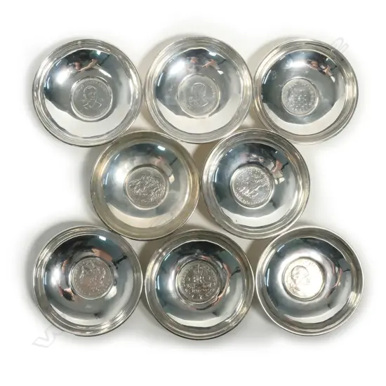Eight small silver dishes set with coins to the centre