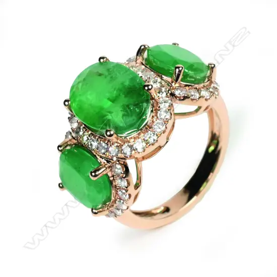 A 14ct gold emerald and diamond halo trilogy ring