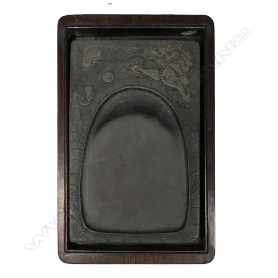 A vintage Oriental hardwood boxed inkstone, rosewood box with inlaid calligraphy to the lid, the inkstone with shaped well framed by a dragon in relief. 245 x 145 x 60mm.