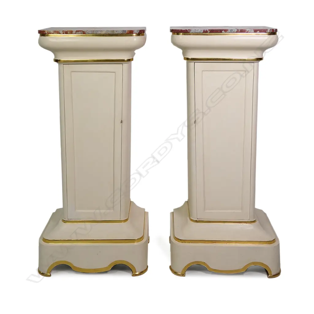 A pair of stylish French plinths, cream painted gesso and parcel gilt with rouge griotte marble tops, each of tapering shape with concealed cabinets surmounted by swollen capitals and raised from cavetto plinths. Marble repaired to one. 610 x 410 x 1350mm. Image 1++