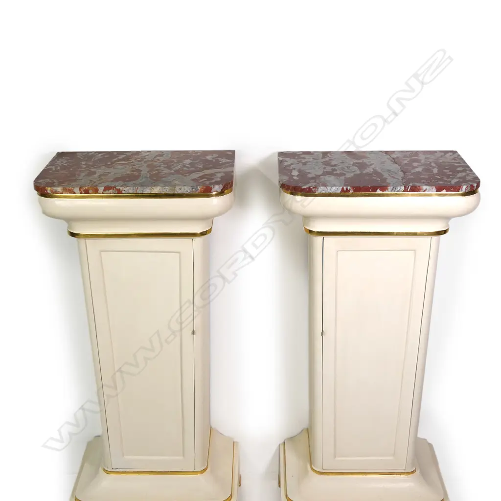 A pair of stylish French plinths, cream painted gesso and parcel gilt with rouge griotte marble tops, each of tapering shape with concealed cabinets surmounted by swollen capitals and raised from cavetto plinths. Marble repaired to one. 610 x 410 x 1350mm. Image 1++