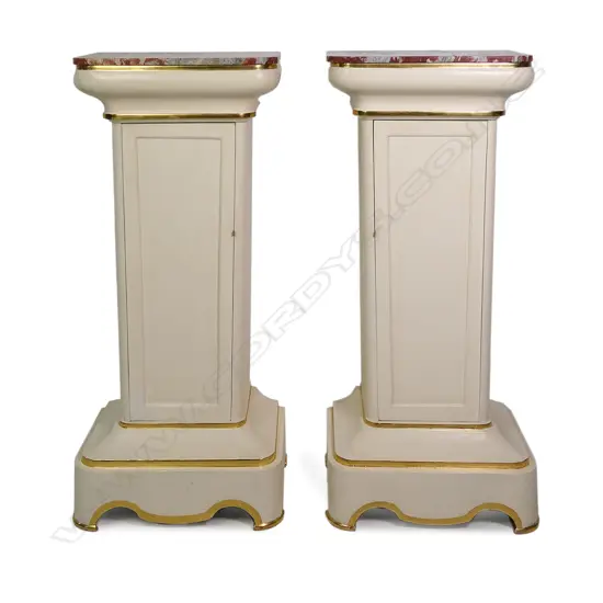 A pair of stylish French plinths, cream painted gesso and parcel gilt with rouge griotte marble tops, each of tapering shape with concealed cabinets surmounted by swollen capitals and raised from cavetto plinths. Marble repaired to one. 610 x 410 x 1350mm.