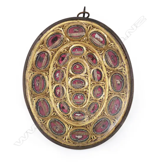 A portable reliquary, a brass frame enclosing braided gilt sections each containing particular saints' minute body remains, under glass. 115 x 140mm.