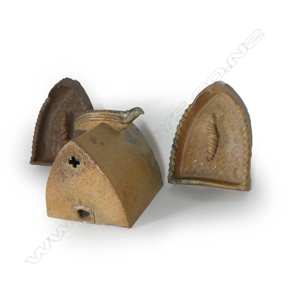 Mike O'Donnell (Taraiki Pottery) 'House of Manu', salt glazed stoneware three-piece sculpture, the 'House' with stylised bird form to the roof apex, inscribed roof, the end with pierced cross and lower opening with koru impressed decoration, the two flanking doorway forms with stylised open winged birds to the top, each incorporating a large sculpted volute scroll on repeating shell impressed textured ground, heavy salt glazed effects in part. The house 330 x 340 x 355mm, the doorway's H.420mm. Image 1++