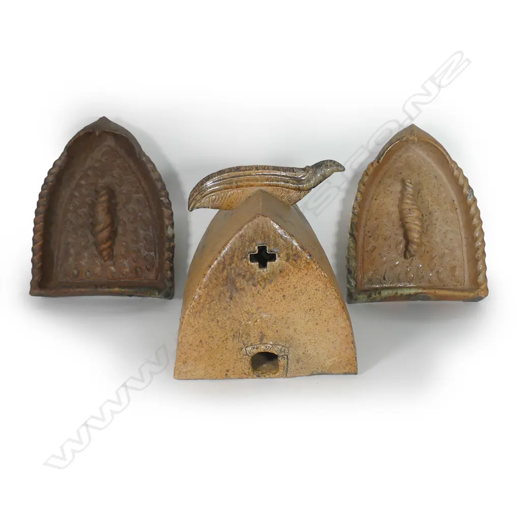 Mike O'Donnell (Taraiki Pottery) 'House of Manu', salt glazed stoneware three-piece sculpture, the 'House' with stylised bird form to the roof apex, inscribed roof, the end with pierced cross and lower opening with koru impressed decoration, the two flanking doorway forms with stylised open winged birds to the top, each incorporating a large sculpted volute scroll on repeating shell impressed textured ground, heavy salt glazed effects in part. The house 330 x 340 x 355mm, the doorway's H.420mm. Image 1++