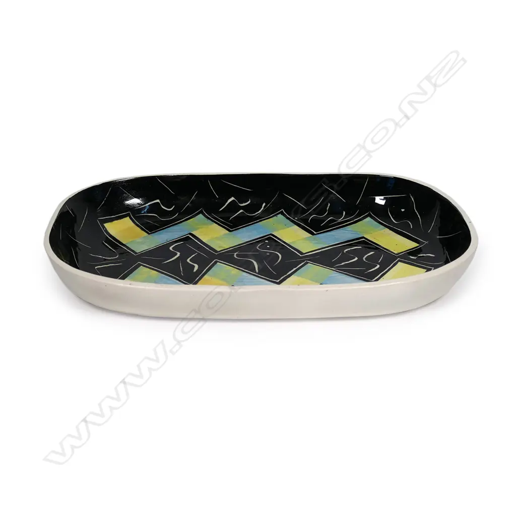Warren Tippett rectangular dish, abstract blue and yellow zig-zag decoration on black ground with S-scroll and lineal decoration. Signed and dated '83. 317 x 195mm Image 1++