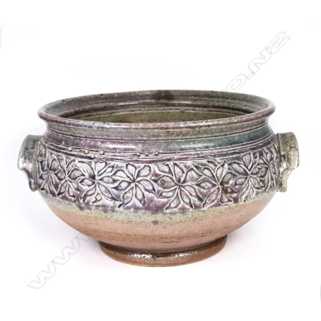 Warren Tippett decorated bowl, impressed band of repeating floral pattern, green and mauve glaze, two hooded handles. Dia.240mm. Labelled and dated '82. Provenance: Ex. the collection of Jacqui and Graeme Storm. Image 1++