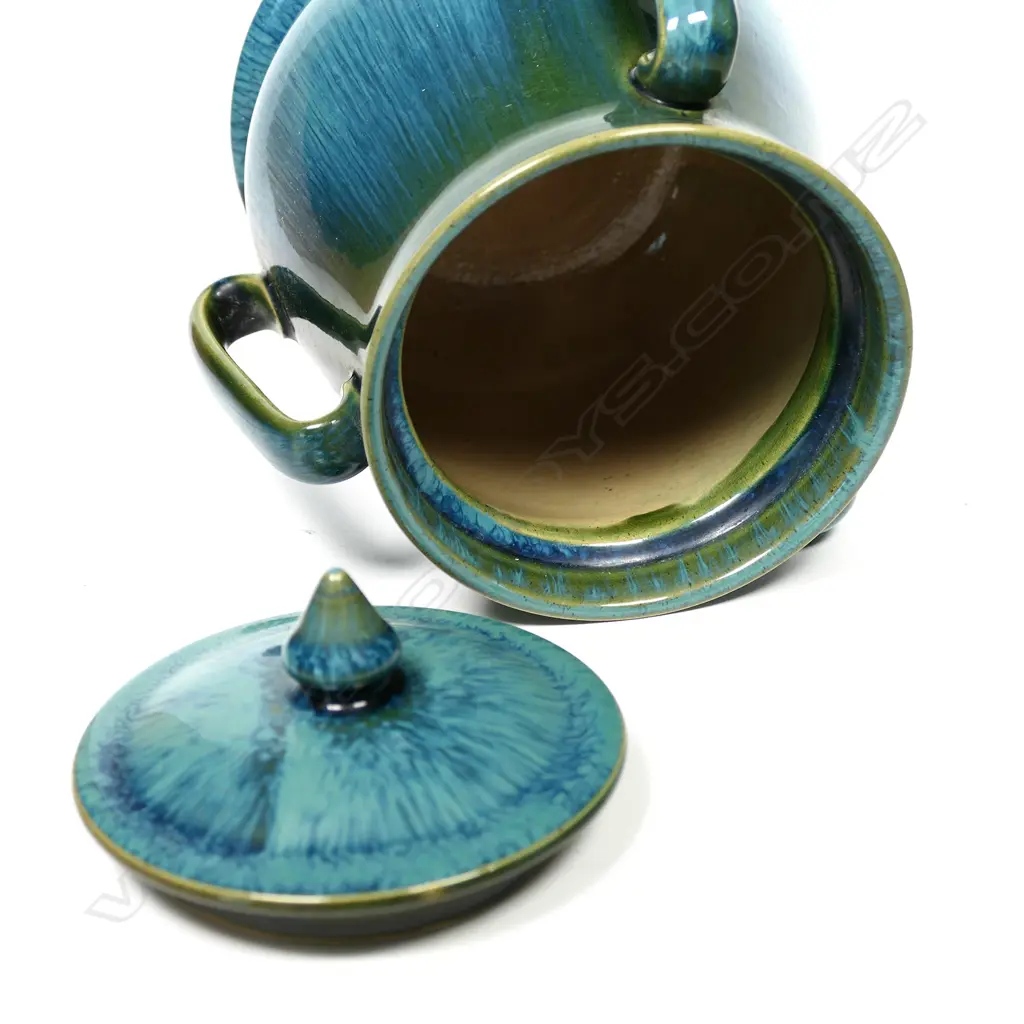 An Ashby Guild pottery lidded barrel, tapering shape on circular spreading foot, three elongated loop handles to the side. Streaked tonal blue green glaze. Impressed stamp. H.170mm Image 1++