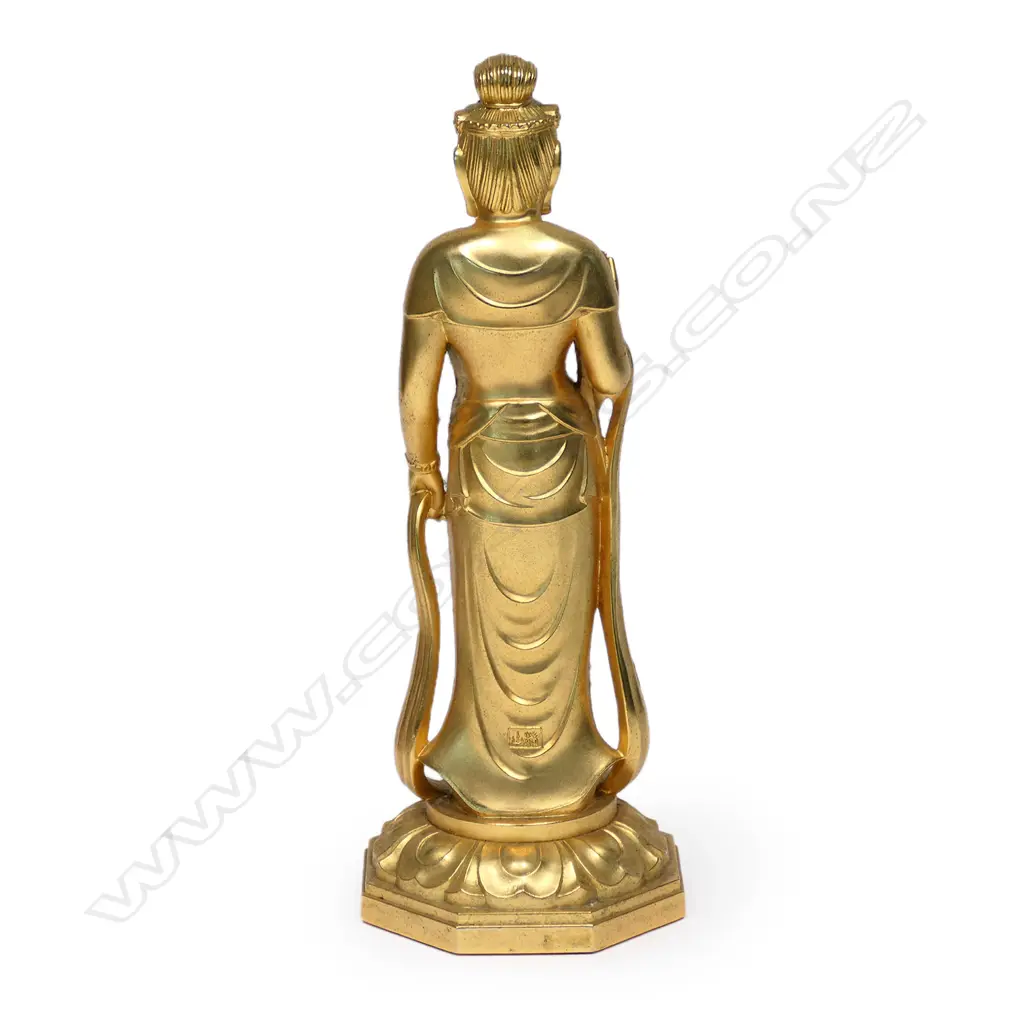 A quality mid/late 20thC gilded bronze standing buddha, the right hand in Shuni mudra, in traditional robes with long drape. Raised on lotus throne. A gem set to the forehead. H.215mm. The hand pose gesture is used to improve intuition, alertness, and sensory powers. It also purifies your emotions and thoughts. Image 1++