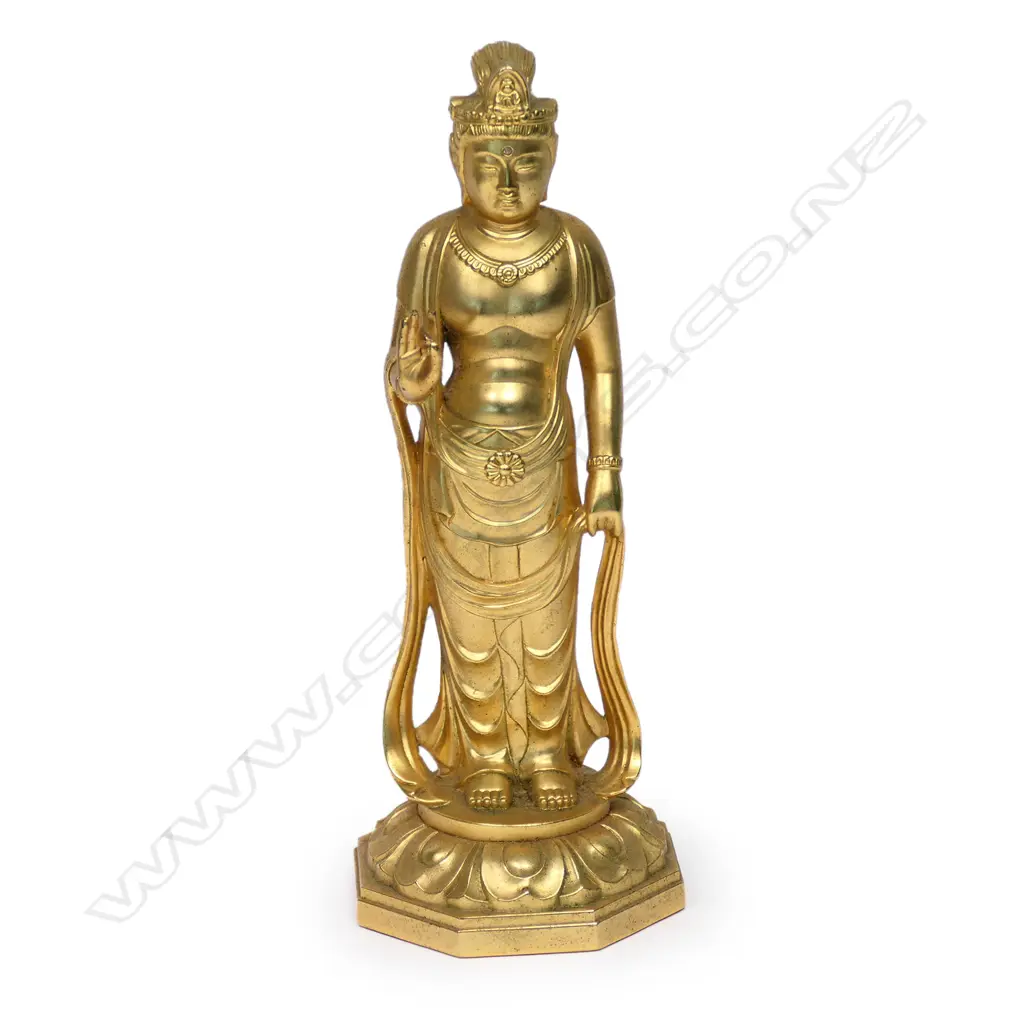 A quality mid/late 20thC gilded bronze standing buddha, the right hand in Shuni mudra, in traditional robes with long drape. Raised on lotus throne. A gem set to the forehead. H.215mm. The hand pose gesture is used to improve intuition, alertness, and sensory powers. It also purifies your emotions and thoughts. Image 1++