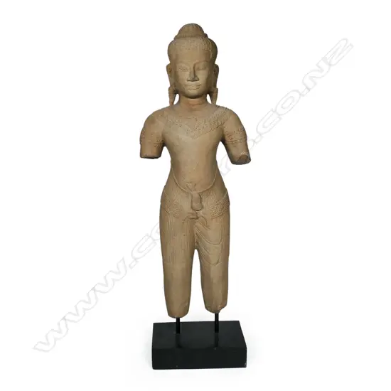 A 20thC Khmer inspired statue of a female divinity, finely detailed, with serene face, almond shaped eyes below her arched brow. Long pendulous pierced earlobes, finely braided tresses and secured by a braided band with a mango leaf shaped accent. Raised on ebonised rectangular stand. H.715mm.