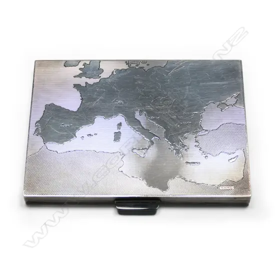 An unusual silver Art Deco cigarette case by Asprey & Co, London, the lid engraved with a map of Western Europe and the Mediterranean, with the capital cities named. The cartography detailed with various plain and machine engraved grounds. Black onyx thumbpiece, the interior with a hinged solid retaining bar. London 1936. 115 x 82 x 10mm. 189gm.
