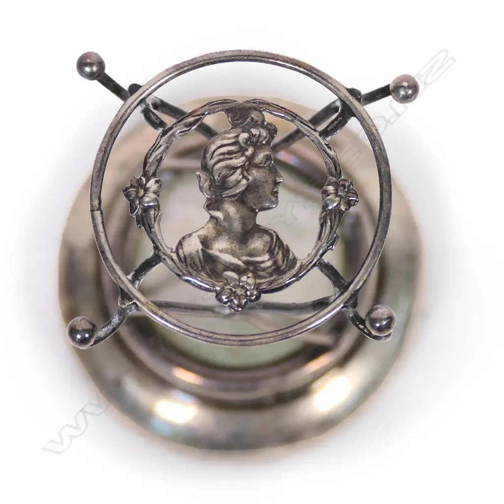 An Edwardian silver hat pin cushion stand, the top with the portrait bust of a maiden in profile. Chester 1908. H.74mm. Image 1++