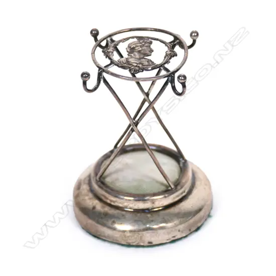 An Edwardian silver hat pin cushion stand, the top with the portrait bust of a maiden in profile. Chester 1908. H.74mm.