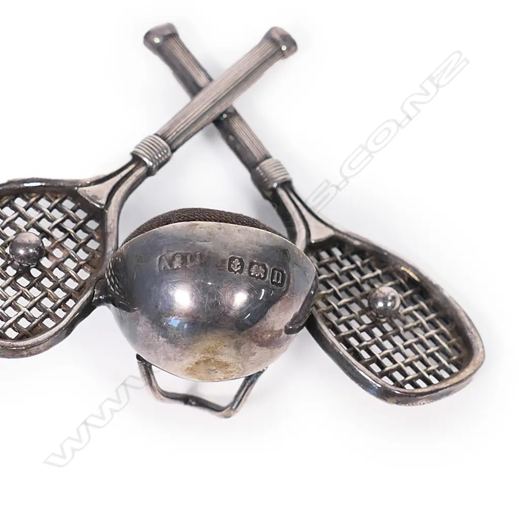 An early 20thC rare silver tennis themed pin cushion, the stand as two crossed rackets centred with balls flanking the cushion. Birmingham 1912. By Adie & Lovekin Ltd. H.50mm. Image 1++