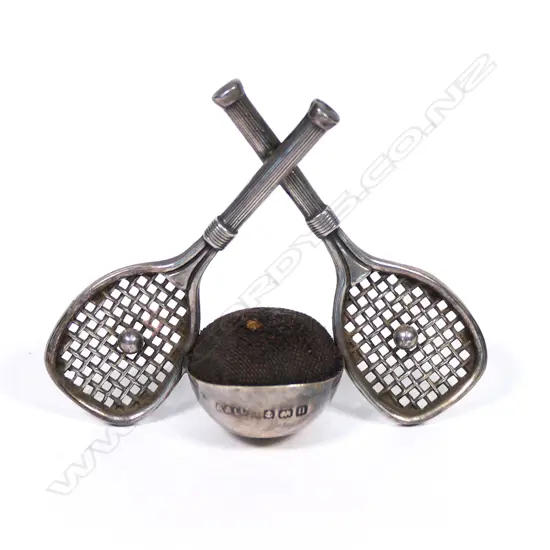 An early 20thC rare silver tennis themed pin cushion, the stand as two crossed rackets centred with balls flanking the cushion. Birmingham 1912. By Adie & Lovekin Ltd. H.50mm.