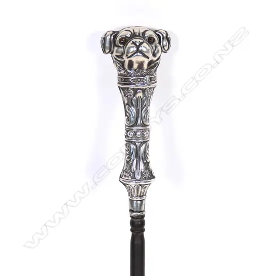 An uncommon Edwardian silver dog handled boot hook, the pug type dog with glass eyes, with collar and leafy and floral bands, steel shaft. L.230mm. Birmingham 1907, by Crisford & Norris Ltd. Minor faults consistent with age.