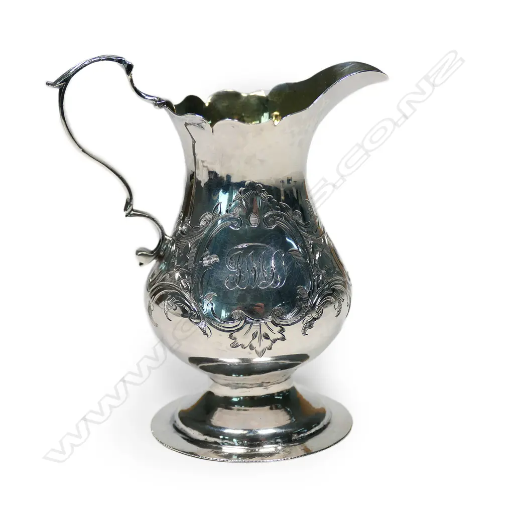 A Geo. III silver baluster cream jug, with serpentine rim, acanthus capped double scroll handle, foliate engraved body, gilt washed interior, raised on circular foot. London 1765 by Wm. Kinman (Grimwades mark 3210). H.105mm. 70gm Image 1++