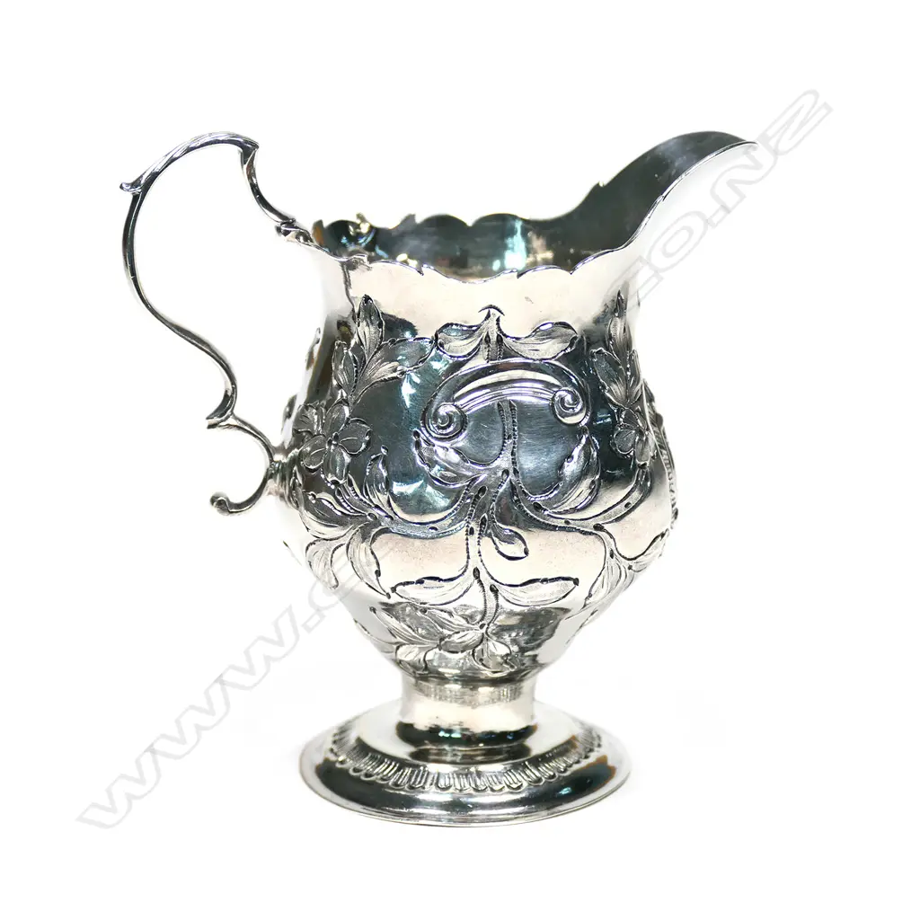 A Geo. III silver baluster cream jug, with serpentine rim, acanthus capped double scroll handle, foliate repousse body, raised on circular foot. London 1770, maker's mark: NS/AN. H.105mm. 70gm Image 1++