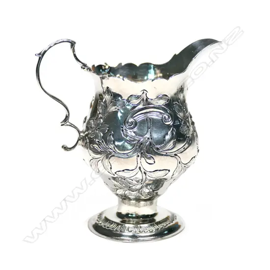 A Geo. III silver baluster cream jug, with serpentine rim, acanthus capped double scroll handle, foliate repousse body, raised on circular foot. London 1770, maker's mark: NS/AN. H.105mm. 70gm