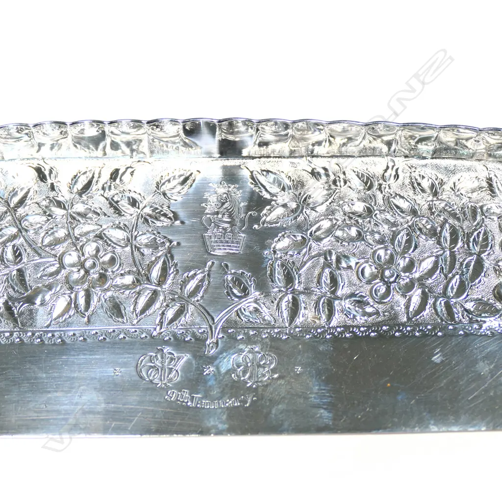A Vict. silver crumb tray with simulated ivory handle, the blade repousse decorated with roses and anniversary engraving for 1867-1892; along with crest: from a mural coronet a lion's head gorged and ducally crowned. (Handle split) L.320mm, Total 210gm Image 1++