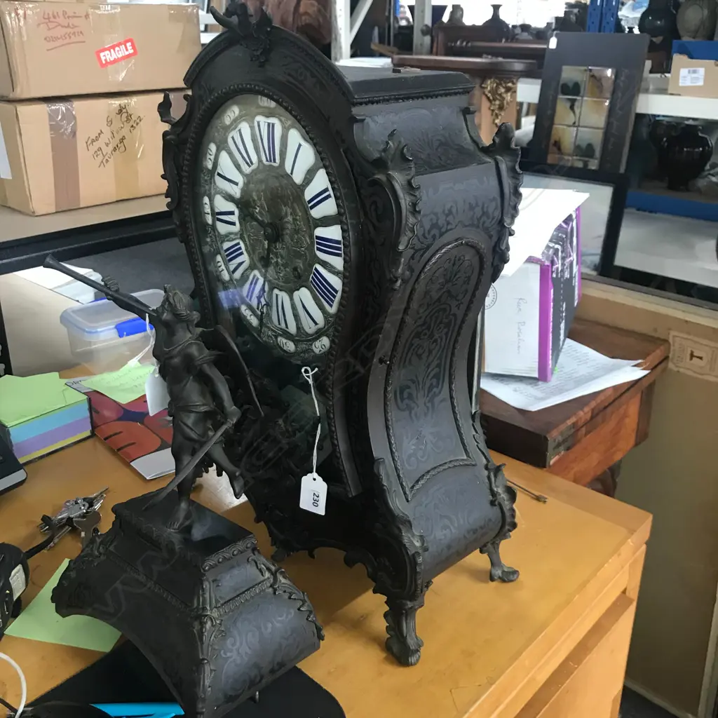 A Louis XVI-style mantel clock, the shaped case inlaid with cut brass Boulle work on black lacquered ground and heavily tarnished rococo ormolu mounts, surmounted by a pagoda top crowned by a standing heraldic angel figure. The cast dial with white enamel hour cartouches with blue Roman numerals, gong striking movement, sunburst pendulum above a sloping checkered floor, behind a glazed door mounted with a floral adorned putti. H.640mm. Image 1++