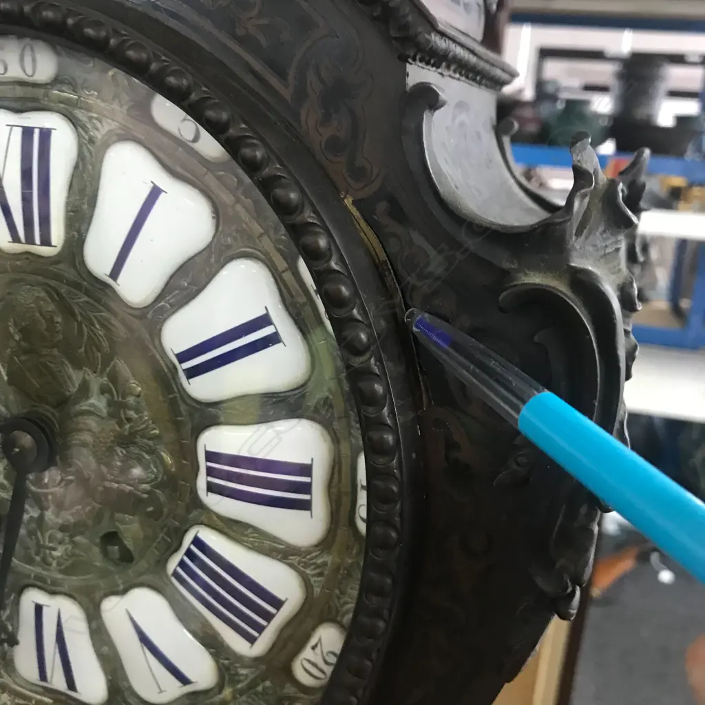 A Louis XVI-style mantel clock, the shaped case inlaid with cut brass Boulle work on black lacquered ground and heavily tarnished rococo ormolu mounts, surmounted by a pagoda top crowned by a standing heraldic angel figure. The cast dial with white enamel hour cartouches with blue Roman numerals, gong striking movement, sunburst pendulum above a sloping checkered floor, behind a glazed door mounted with a floral adorned putti. H.640mm. Image 1++
