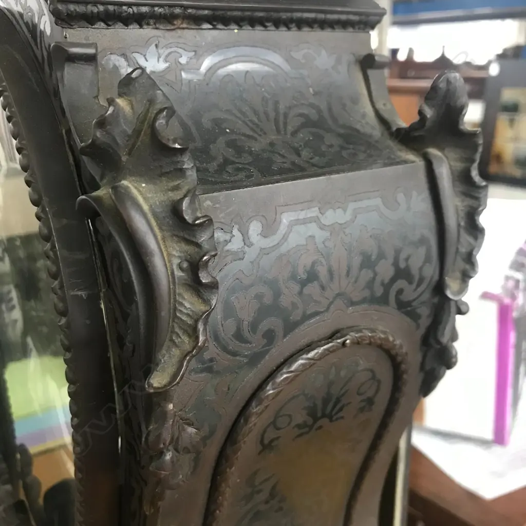 A Louis XVI-style mantel clock, the shaped case inlaid with cut brass Boulle work on black lacquered ground and heavily tarnished rococo ormolu mounts, surmounted by a pagoda top crowned by a standing heraldic angel figure. The cast dial with white enamel hour cartouches with blue Roman numerals, gong striking movement, sunburst pendulum above a sloping checkered floor, behind a glazed door mounted with a floral adorned putti. H.640mm. Image 1++