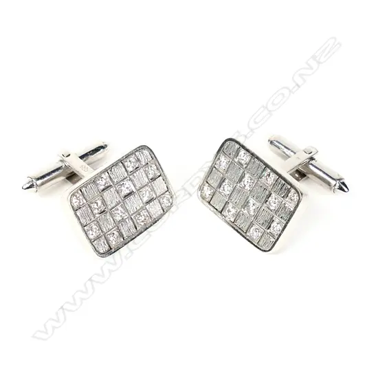 A pair of diamond set 14ct white gold panel cufflinks, each of oblong set with a checkerboard of 12 round brilliant cut diamonds on hinged bar backs. The 24 diamonds of approx. TDW 1.20ct. Valuation available.