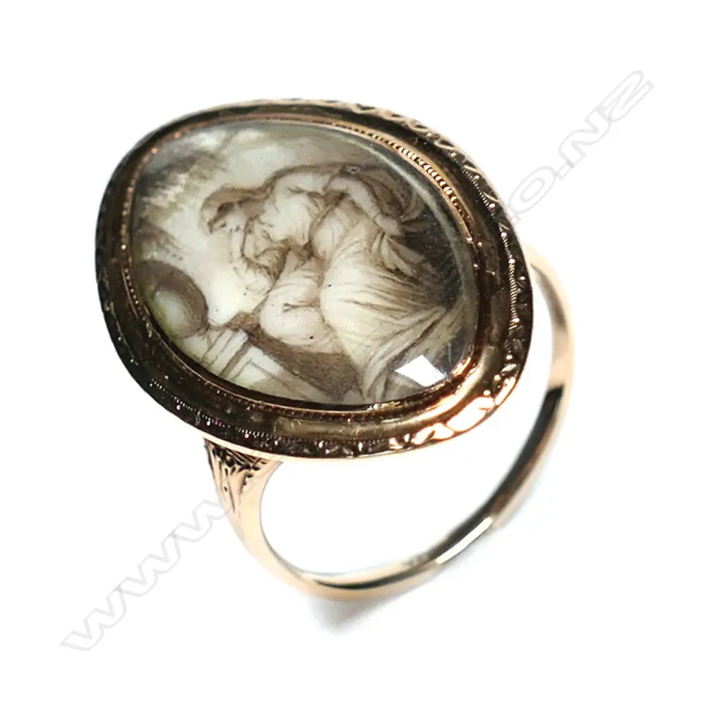 A Georgian mourning ring, the unmarked gold marquise shape mount set with an ivory panel under rock crystal decorated with a woman weeping over a tombstone, woven hair in the base. Image 1++