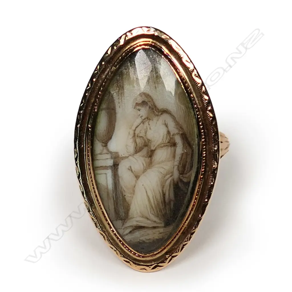 A Georgian mourning ring, the unmarked gold marquise shape mount set with an ivory panel under rock crystal decorated with a woman weeping over a tombstone, woven hair in the base. Image 1++