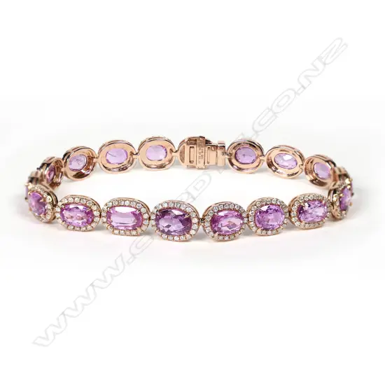 A 14ct rose gold pink sapphire and diamond halo bracelet, eighteen oval cut mid purplish-pink sapphires (some inclusions), claw set and surrounded by a halo of round brilliant cut diamonds (H-J colour, SI-I1 clarity), push clasp with safety catch, TSW 15.27ct, TDW 2.15ct, L.185mm.