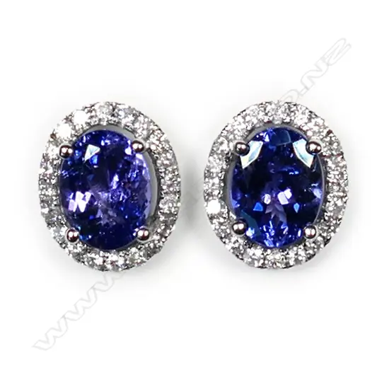 A pair of 14ct white gold tanzanite and diamond halo earrings, each earring set with a 1.17ct oval cut violet blue tanzanite (moderate to heavy inclusions), claw set and surrounded by twenty round brilliant cut diamonds (colour G-J, clarity I1-I2), posts for pierced ears, TTW 2.35ct, TDW 0.38ct.