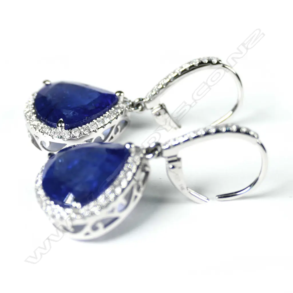 A pair of 14ct white gold tanzanite and diamond halo drop earrings, each earring set with a 5.82ct pear cut purplish-blue tanzanite (eye visible inclusions), claw set, surrounded by thirty-nine round brilliant cut diamonds (H-I colour, SI2-I2 clarity), lever backs for pierced ears, TTW 11.64ct TDW 0.63ct. Image 1++