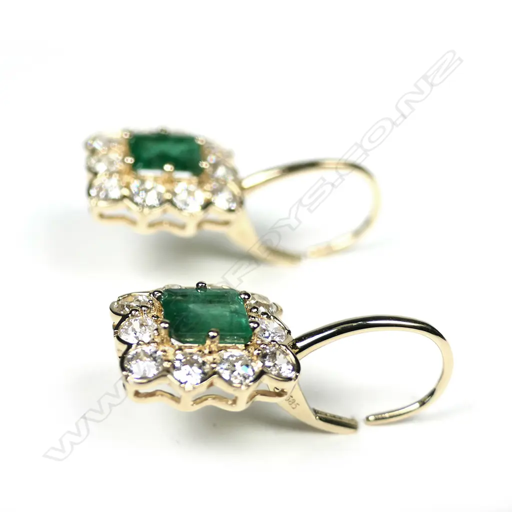 A pair of 14ct white gold emerald and diamond drop halo earrings, each earring set with two oval cut, bluish green Zambian emeralds (eye visible inclusions), claw set in yellow gold, each surrounded by a halo of round brilliant cut diamonds (G-H colour, SI1-I2 clarity), posts for pierced ears, TEW 19.59ct, TDW 0.91ct. Image 1++