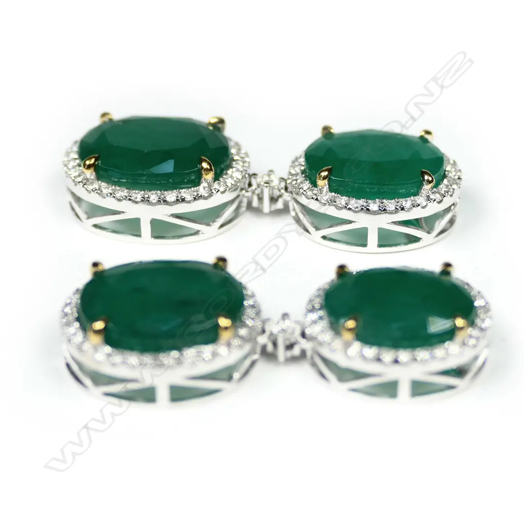 A pair of 14ct white gold emerald and diamond drop halo earrings, each earring set with two oval cut, bluish green Zambian emeralds (eye visible inclusions), claw set in yellow gold, each surrounded by a halo of round brilliant cut diamonds (G-H colour, SI1-I2 clarity), posts for pierced ears, TEW 19.59ct, TDW 0.91ct. Image 1++