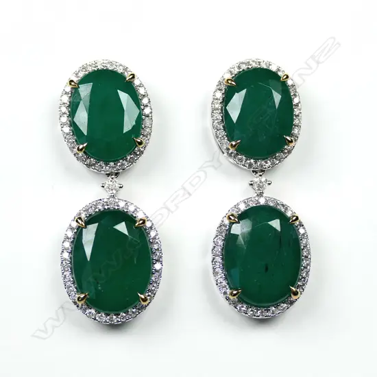 A pair of 14ct white gold emerald and diamond drop halo earrings, each earring set with two oval cut, bluish green Zambian emeralds (eye visible inclusions), claw set in yellow gold, each surrounded by a halo of round brilliant cut diamonds (G-H colour, SI1-I2 clarity), posts for pierced ears, TEW 19.59ct, TDW 0.91ct.