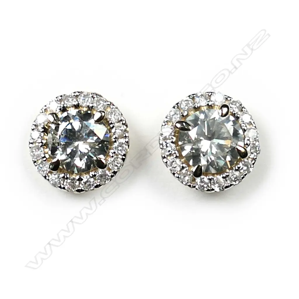 A pair of 14ct gold diamond halo stud earrings, each earring set with a 0.58ct round brilliant cut diamonds (M-N colour, SI2-I1 clarity), claw set and surrounded by sixteen round brilliant cut diamonds (J-K colour, SI1-I2 clarity), posts for pierced ears, TDW 1.33ct. Image 1++