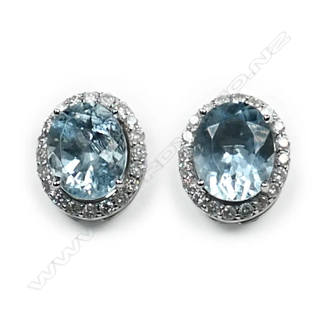 A pair of 14ct white gold aquamarine and diamond halo stud earrings, each earring set with a 2.18ct oval cut light blue aquamarine (eye clean clarity), claw set and surrounded by twenty round brilliant cut diamonds (H-I colour, SI2-I1 clarity), posts for pierced ears, TAW 4.36ct, TDW  0.58ct. Image 1++
