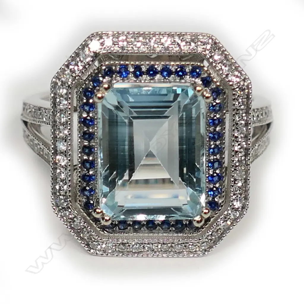 A 14k white gold aquamarine diamond and sapphire ring, the octagonal cut 3.13ct aquamarine framed by rows of small sapphires and diamonds, further diamonds to the forked shoulders. With AIG certificate and valuation available. Image 1++