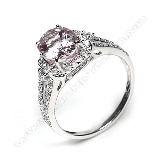 A 14ct white gold morganite and diamond vintage style halo ring, a 1.74ct oval cut light purplish pink morganite (eye clean clarity), claw set and surrounded by round brilliant cut diamonds with further diamonds set to the split shoulders, (G-H colour, SI2-I2 clarity), TDW 0.34ct, ring size M.